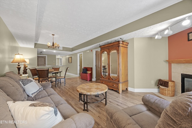 818 Golf View Blvd Unit 1502, Pigeon Forge, TN 37863 - living room with a textured ceiling, a chandelier, light wood-style flooring, and a tile fireplace