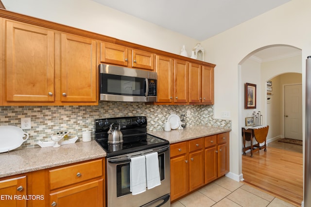 505 Bugaboo Springs Rd, Jonesborough, TN 37659 - kitchen with stainless steel appliances, arched walkways, ornamental molding, brown cabinetry, and backsplash