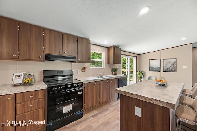 308 Cowan Ln, Lafollette, TN 37766 - kitchen featuring black appliances, under cabinet range hood, light wood-style flooring, a breakfast bar, and light countertops