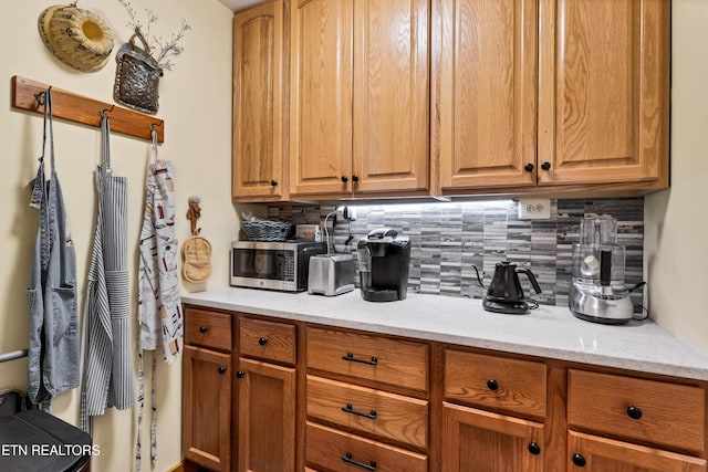 132 Cutter Gap Rd, Townsend, TN 37882 - kitchen featuring stainless steel microwave, backsplash, brown cabinetry, and light stone countertops