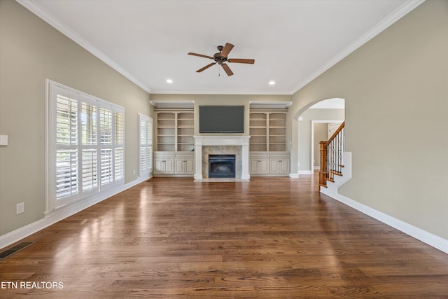 1219 Barton Place Ln, Knoxville, TN 37922 - unfurnished living room featuring ceiling fan, a tile fireplace, arched walkways, crown molding, and built in features