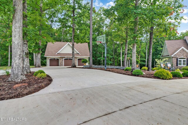 265 Falling Leaf Rd, Jamestown, TN 38556 - view of front facade with concrete driveway, a garage, stone siding, and view of wooded area