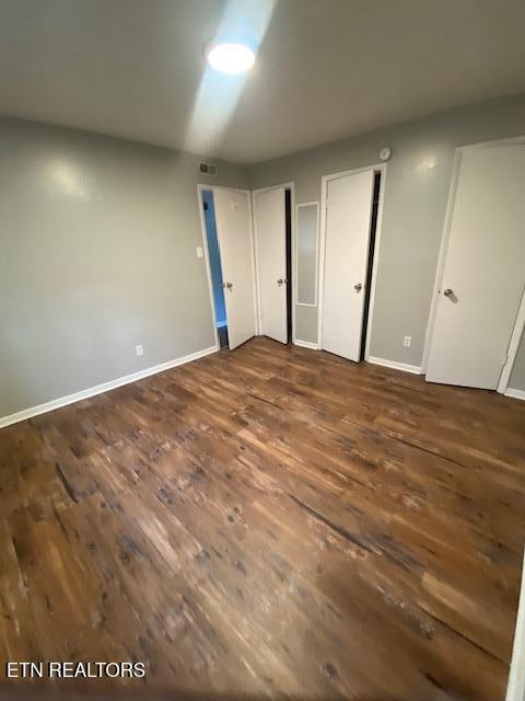 2810 Daybreak Way, Strawberry Plains, TN 37871 - unfurnished bedroom with dark wood-style floors and multiple closets