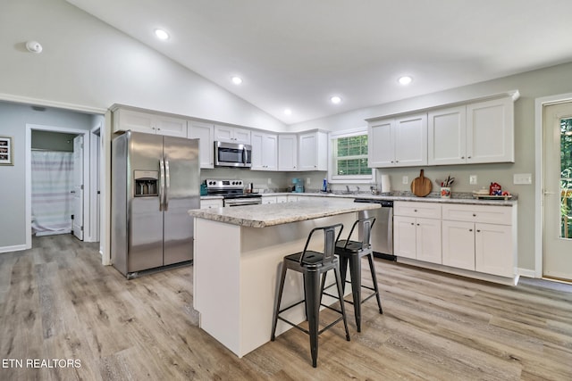 2296 Memory Garden Rd, Jamestown, TN 38556 - kitchen featuring appliances with stainless steel finishes, lofted ceiling, light wood-style flooring, a kitchen island, and a breakfast bar area