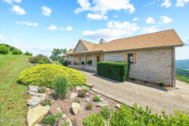 61 Brim Ln, Hilham, TN 38568 - rear view of property featuring brick siding, covered porch, a chimney, and roof with shingles