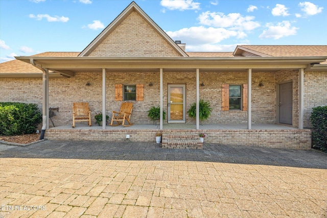 61 Brim Ln, Hilham, TN 38568 - back of house featuring covered porch, brick siding, roof with shingles, and a chimney