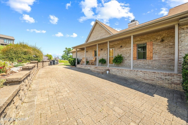 61 Brim Ln, Hilham, TN 38568 - view of property exterior featuring brick siding, a porch, and a chimney
