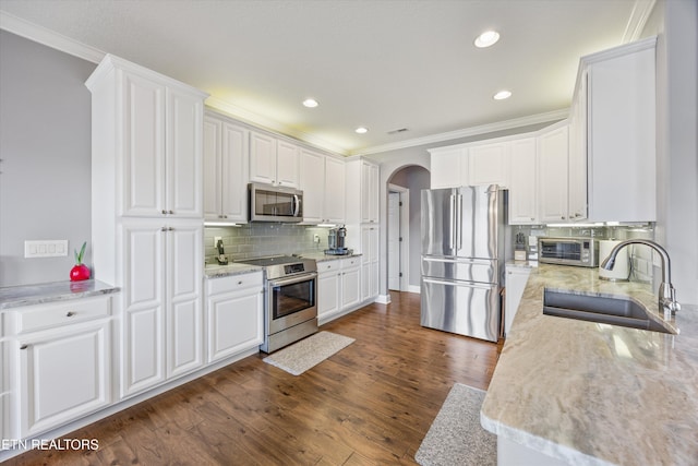 404 Chota Landing Way, Loudon, TN 37774 - kitchen featuring appliances with stainless steel finishes, arched walkways, backsplash, white cabinetry, and ornamental molding