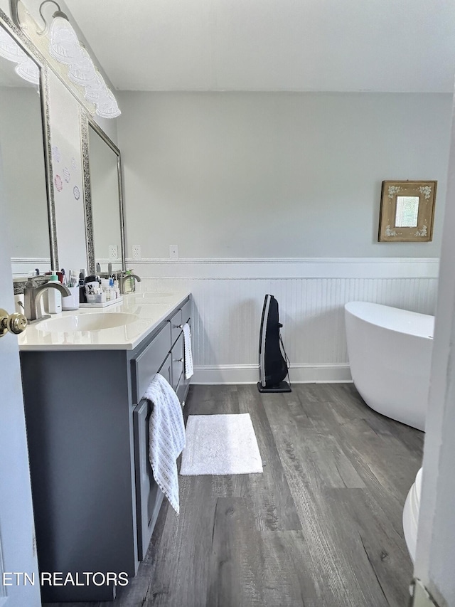 1292 Martin Ln, Lafollette, TN 37766 - bathroom featuring wood finished floors, double vanity, a wainscoted wall, and a soaking tub