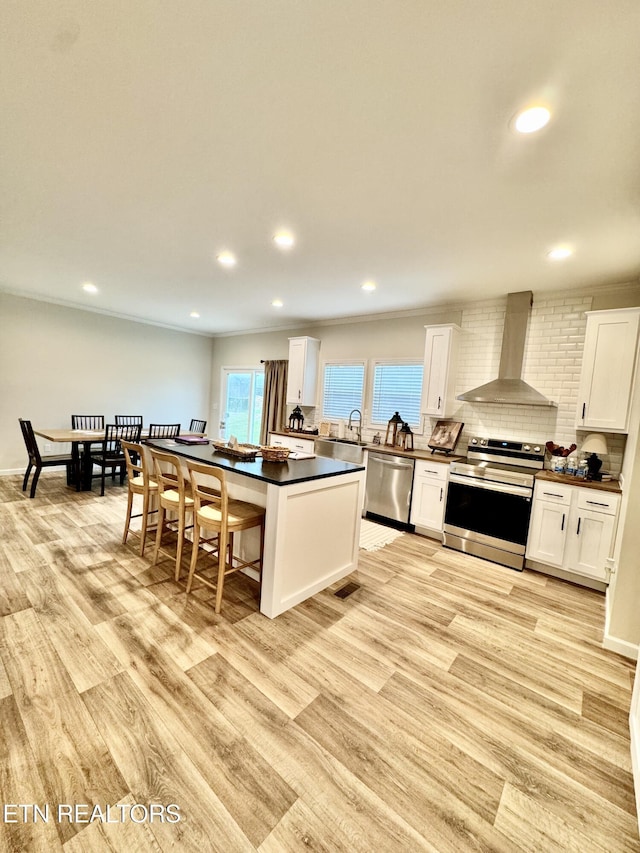 105 Ruby Ln, New Tazewell, TN 37824 - kitchen with appliances with stainless steel finishes, wall chimney range hood, dark countertops, white cabinetry, and recessed lighting