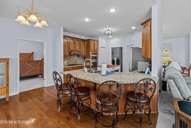 108 Skyline Dr, Dandridge, TN 37725 - kitchen with washer and dryer, double oven, a peninsula, light stone counters, and a kitchen bar