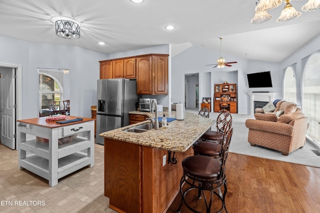 108 Skyline Dr, Dandridge, TN 37725 - kitchen with stainless steel fridge with ice dispenser, a ceiling fan, light stone countertops, brown cabinetry, and a breakfast bar area