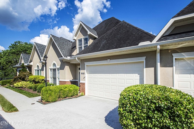 275 Fordham Way, Knoxville, TN 37934 - view of front of home with stucco siding, driveway, a shingled roof, a garage, and brick siding