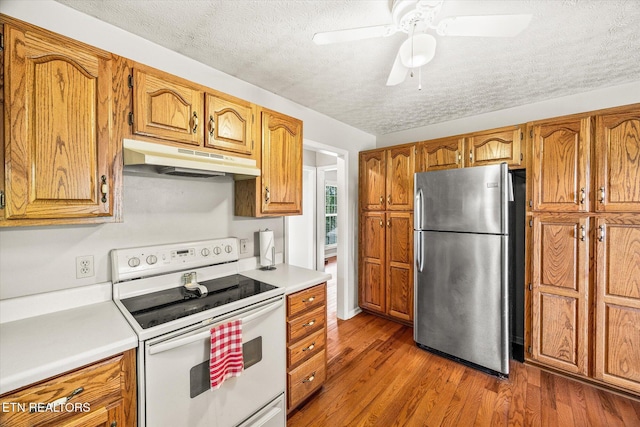 454 Boyd St, Celina, TN 38551 - kitchen with freestanding refrigerator, white electric range, under cabinet range hood, a textured ceiling, and wood finished floors