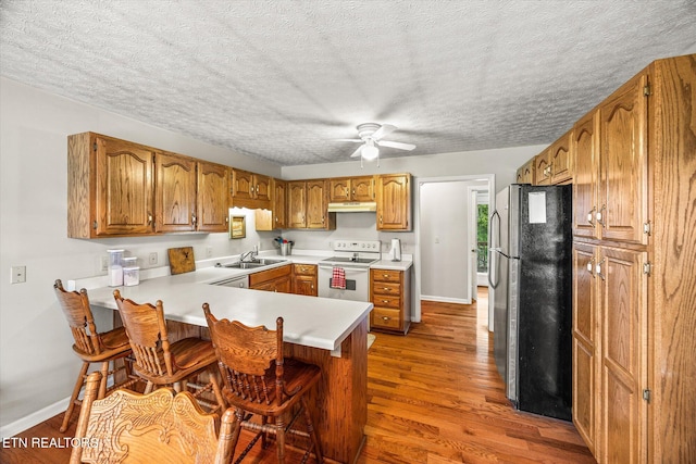 454 Boyd St, Celina, TN 38551 - kitchen featuring freestanding refrigerator, white range with electric stovetop, a peninsula, wood finished floors, and a textured ceiling