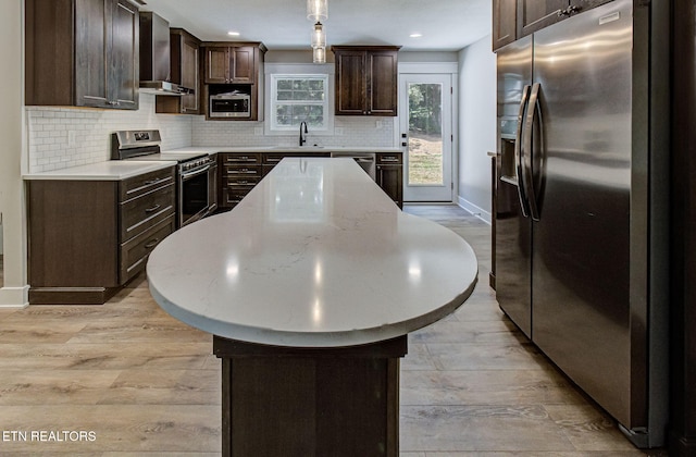 516 Golden Harvest Rd, Knoxville, TN 37934 - kitchen with stainless steel appliances, wall chimney exhaust hood, a kitchen island, dark brown cabinets, and light wood-style flooring