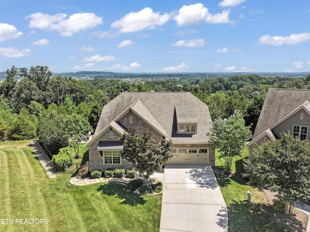 1273 Bishops View Ln, Knoxville, TN 37932 - view of front of house featuring stone siding, an attached garage, concrete driveway, a front lawn, and a wooded view