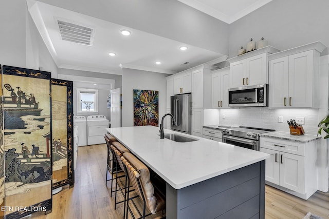 2570 NE Spring Creek Dr, Cleveland, TN 37311 - kitchen featuring stainless steel appliances, independent washer and dryer, ornamental molding, backsplash, and a kitchen bar