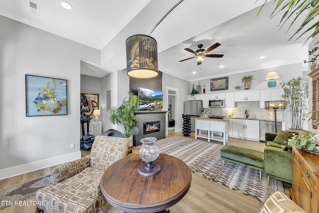2570 NE Spring Creek Dr, Cleveland, TN 37311 - living area with light wood-style floors, ceiling fan, a glass covered fireplace, recessed lighting, and ornamental molding