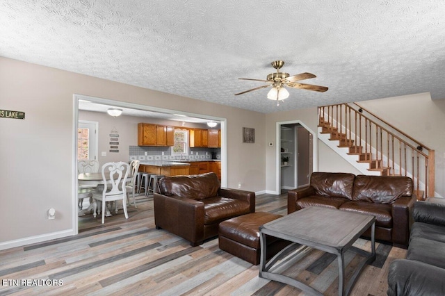 2270 Cove Pointe Rd, Lafollette, TN 37766 - living room featuring ceiling fan, light wood-style floors, a textured ceiling, and stairs