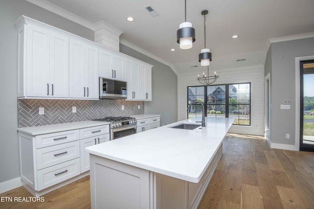 256 Watercrest Dr, Vonore, TN 37885 - kitchen with appliances with stainless steel finishes, crown molding, a kitchen island with sink, decorative backsplash, and light countertops