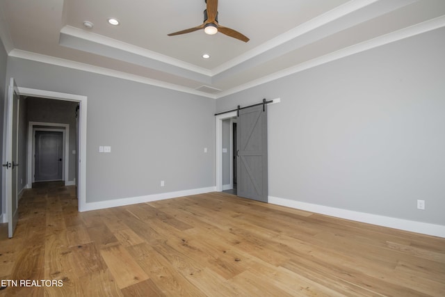 256 Watercrest Dr, Vonore, TN 37885 - unfurnished bedroom featuring a raised ceiling, ornamental molding, a barn door, recessed lighting, and light wood-style flooring