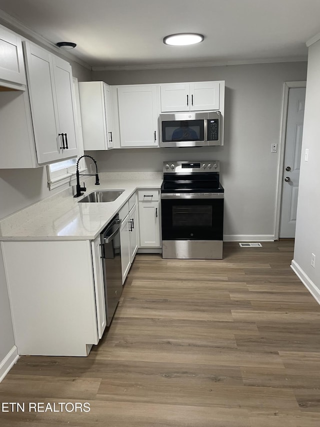 3431 Skyline Dr, Knoxville, TN 37914 - kitchen with appliances with stainless steel finishes, white cabinetry, light wood finished floors, and ornamental molding
