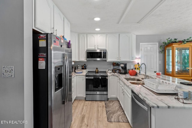 133 Rolling Hls, Rutledge, TN 37861 - kitchen with stainless steel appliances, white cabinetry, a peninsula, light wood-type flooring, and light stone counters