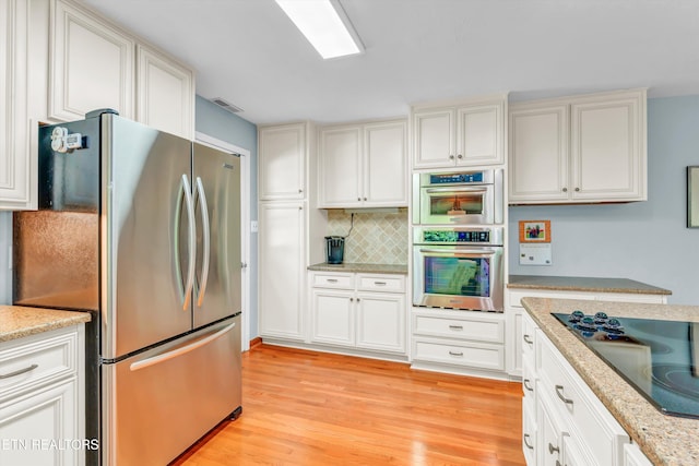 127 Newhaven Rd, Oak Ridge, TN 37830 - kitchen with appliances with stainless steel finishes, light wood finished floors, decorative backsplash, white cabinets, and light stone countertops