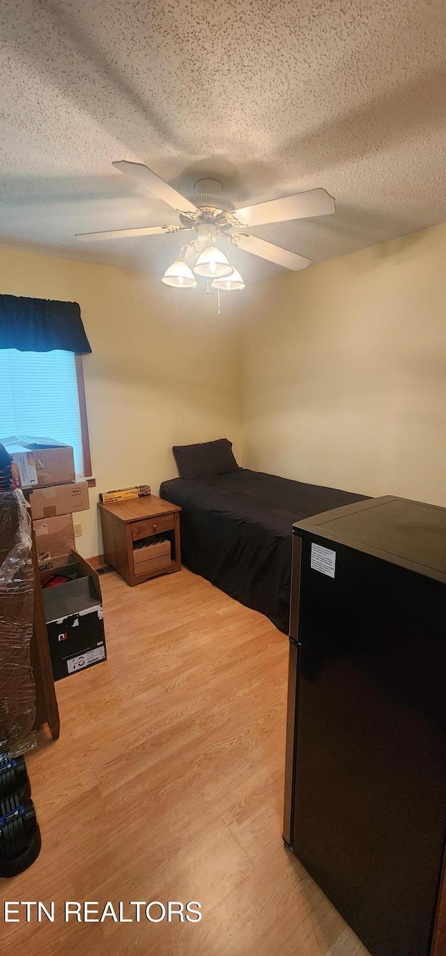 191 Ashley Ln, Oneida, TN 37841 - bedroom featuring fridge, a textured ceiling, light wood-type flooring, and a ceiling fan