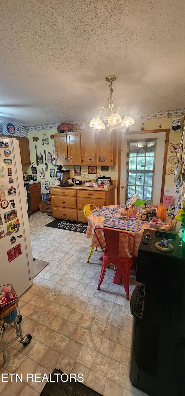 191 Ashley Ln, Oneida, TN 37841 - kitchen featuring freestanding refrigerator, a textured ceiling, a chandelier, brown cabinets, and pendant lighting