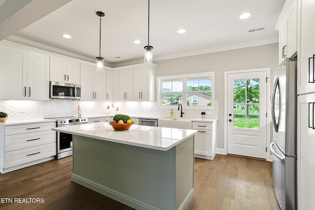 7245 Deville Way, Powell, TN 37849 - kitchen with stainless steel appliances, ornamental molding, backsplash, white cabinetry, and a center island