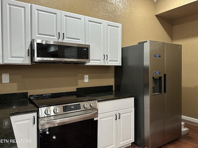 901 Kyle St, Lafollette, TN 37766 - kitchen featuring appliances with stainless steel finishes, white cabinetry, dark wood-style flooring, a textured wall, and dark stone countertops