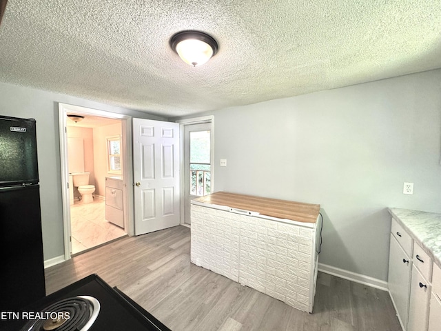 914 S 13th St, Lafollette, TN 37766 - bedroom with freestanding refrigerator, wood finished floors, a textured ceiling, ensuite bathroom, and washer / clothes dryer
