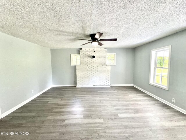 914 S 13th St, Lafollette, TN 37766 - spare room featuring a ceiling fan, wood finished floors, a large fireplace, and a textured ceiling