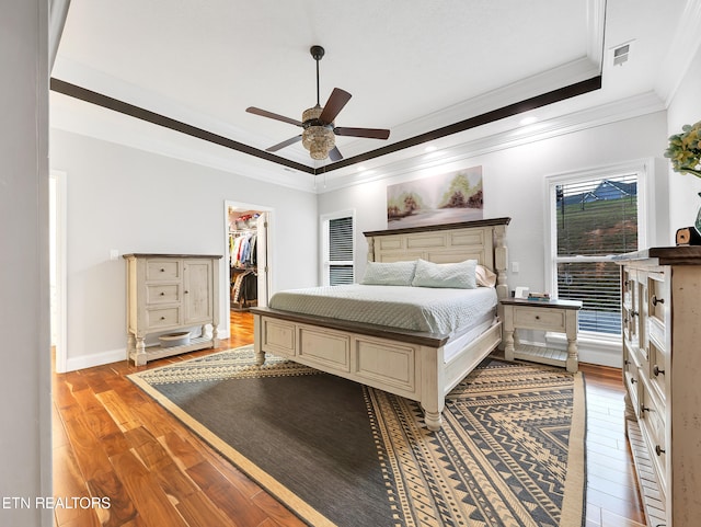 5728 Hickory Valley Rd, Heiskell, TN 37754 - bedroom with crown molding, light wood-style flooring, a spacious closet, a raised ceiling, and a ceiling fan