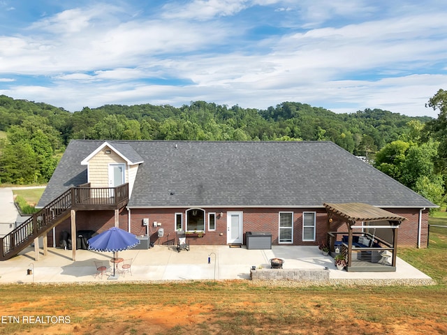 5728 Hickory Valley Rd, Heiskell, TN 37754 - back of property featuring roof with shingles, a patio area, brick siding, a wooded view, and stairs