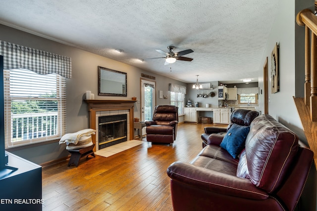 3938 Settlers Trl, Kodak, TN 37764 - living area with a tiled fireplace, a ceiling fan, light wood finished floors, a textured ceiling, and a chandelier