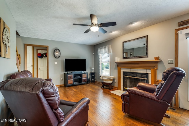 3938 Settlers Trl, Kodak, TN 37764 - living room featuring a ceiling fan, wood-type flooring, a fireplace, and a textured ceiling