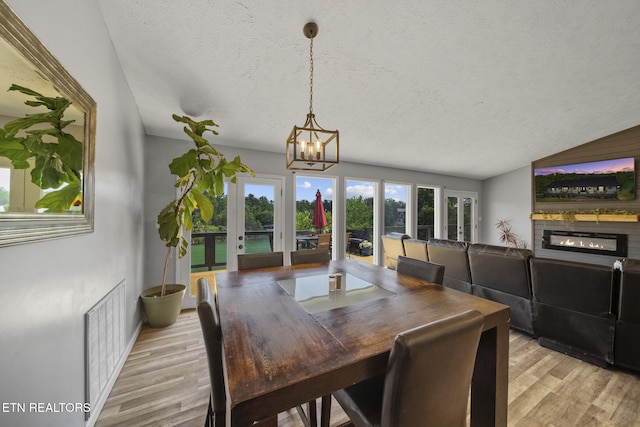 1033 Sunset View Rd, Sevierville, TN 37876 - dining room with light wood finished floors, a chandelier, a textured ceiling, french doors, and a glass covered fireplace