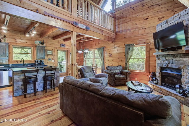 3012 Oak Tree Way, Pigeon Forge, TN 37863 - living room featuring wooden walls, light wood-style flooring, a fireplace, a wood ceiling with exposed beams, and rail lighting