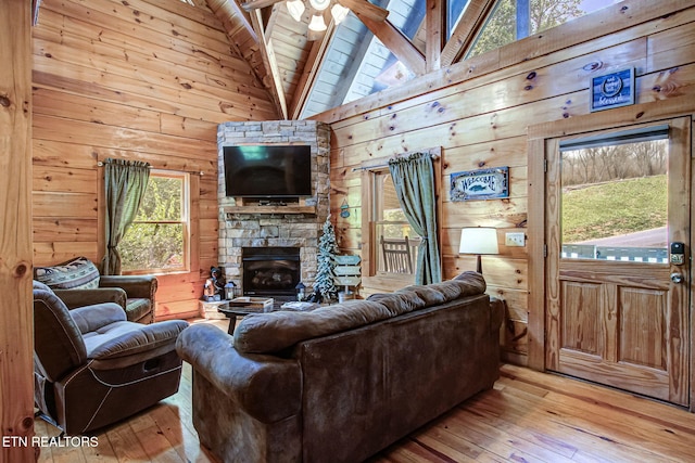 3012 Oak Tree Way, Pigeon Forge, TN 37863 - living area featuring light wood-type flooring, healthy amount of natural light, wood walls, a wood ceiling with exposed beams, and a stone fireplace