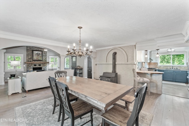 976 Lone Rd, Pioneer, TN 37847 - dining room featuring arched walkways, a fireplace, a textured ceiling, light wood-style floors, and a chandelier