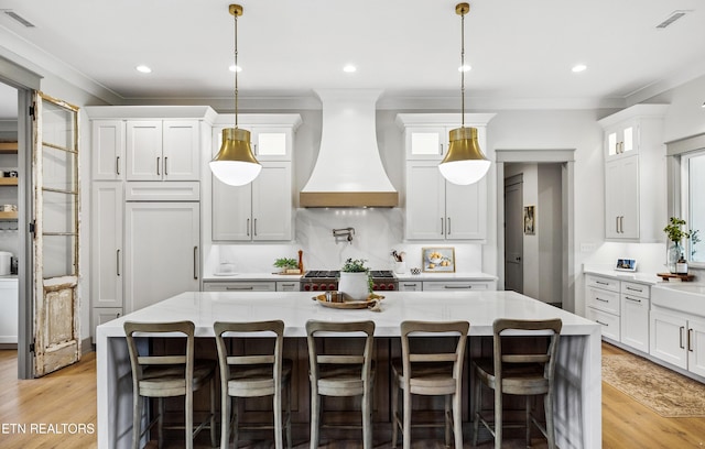 1014 High Springs Rd, Knoxville, TN 37932 - kitchen featuring custom range hood, white cabinetry, light wood finished floors, ornamental molding, and glass insert cabinets