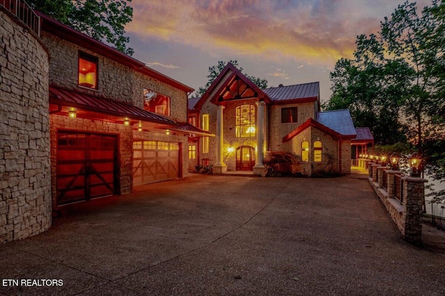 311 Deerwood Ln, Lafollette, TN 37766 - view of front facade with a standing seam roof, an attached garage, driveway, a metal roof, and stone siding