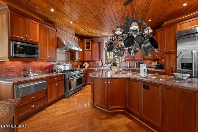 311 Deerwood Ln, Lafollette, TN 37766 - kitchen featuring wall chimney range hood, high end appliances, a warming drawer, brown cabinetry, and recessed lighting