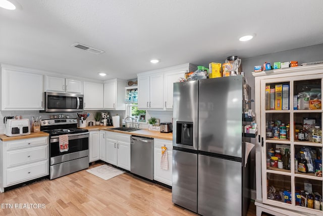121 N Niota Rd, Englewood, TN 37329 - kitchen featuring appliances with stainless steel finishes, white cabinets, light wood-type flooring, wooden counters, and decorative backsplash