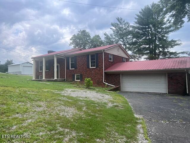 114 Red Cedar Rd, Lafollette, TN 37766 - view of home's exterior with an attached garage, brick siding, driveway, a yard, and a metal roof