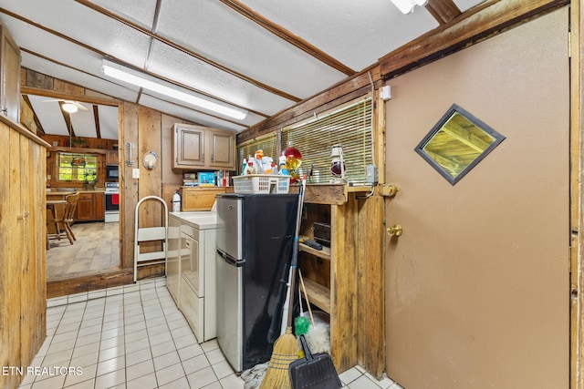 2255 Citico Rd, Vonore, TN 37885 - kitchen featuring freestanding refrigerator, washing machine and clothes dryer, vaulted ceiling, light tile patterned floors, and wooden walls