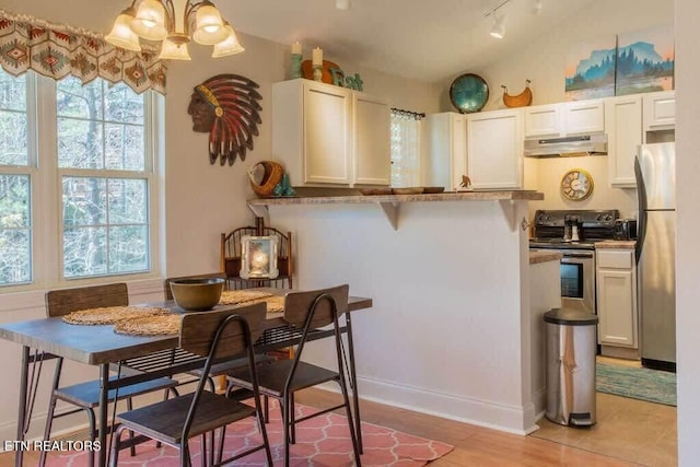 520 Proffitt Rd Unit 1, Gatlinburg, TN 37738 - kitchen with under cabinet range hood, stainless steel appliances, a chandelier, white cabinetry, and a kitchen bar